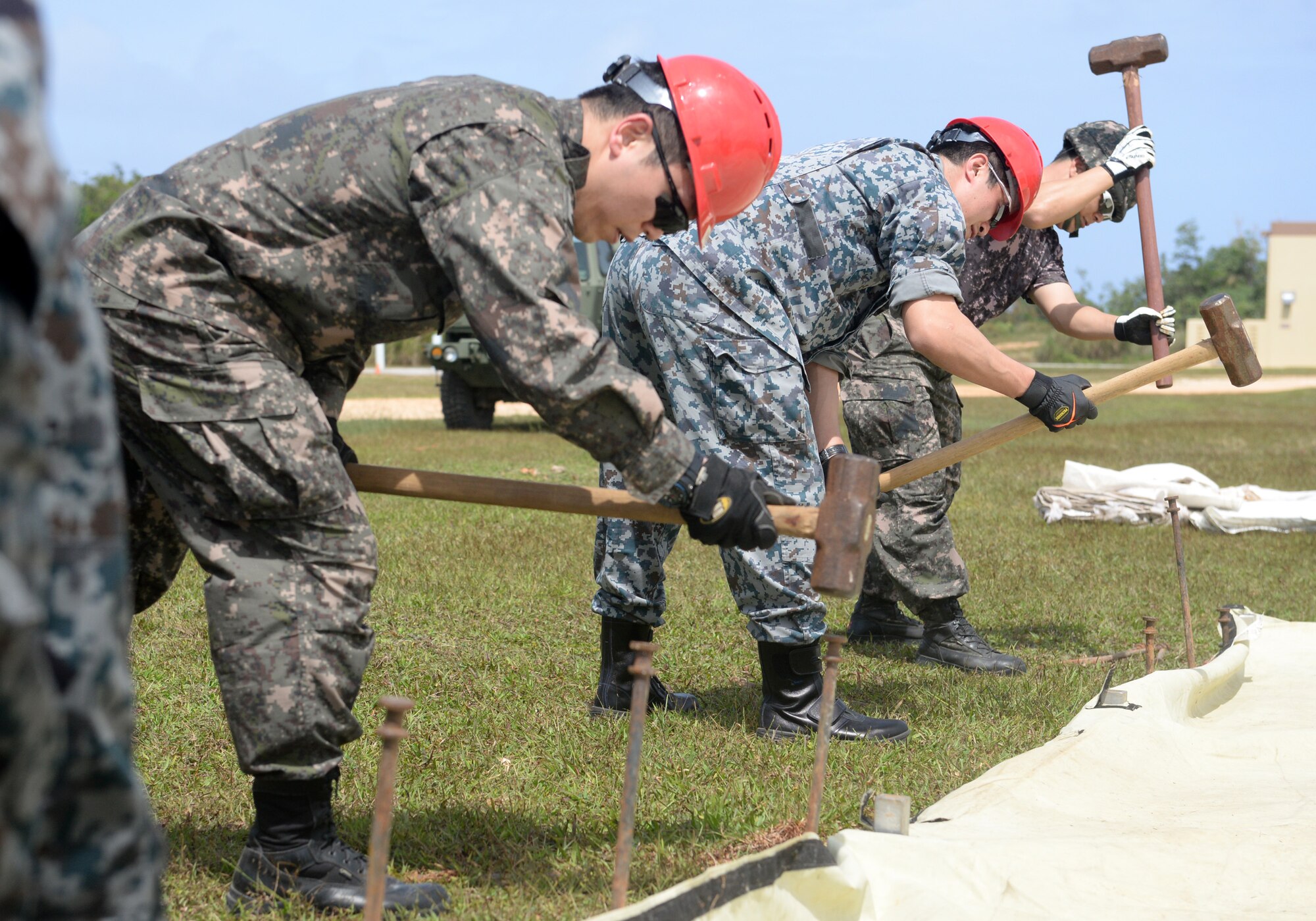 Airmen from the Republic of Korea Air Force and Japan Air Self-Defense Force hammer stakes to prepare a tent during Partner Nation Silver Flag Feb. 13, 2016, at Andersen Air Force Base, Guam. During the first multilateral Partner Nation Silver Flag, instructors from the 554th RED HORSE Squadron partnered with engineers from the Royal Australian Air Force, Republic of Singapore Air Force, ROKAF and the JASDF to exchange information on subjects from command and control, electrical, power production, heavy repair and emergency management. (U.S. Air Force photo/Senior Airman Joshua Smoot)