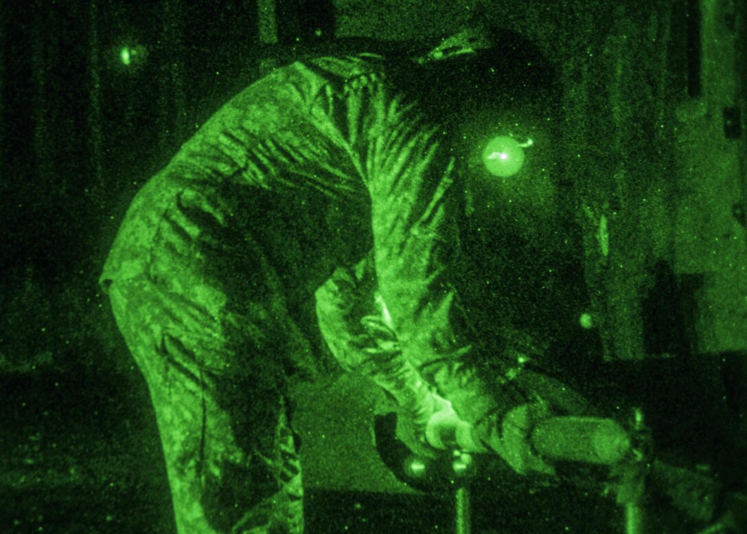 As seen through a night-vision device, a soldier loads a rocket onto an OH-58 Kiowa Warrior helicopter before an aerial gunnery exercise on Marine Corps Outlying Field Atlantic, N.C., Feb. 8, 2016. Army photo by Staff Sgt. Christopher Freeman