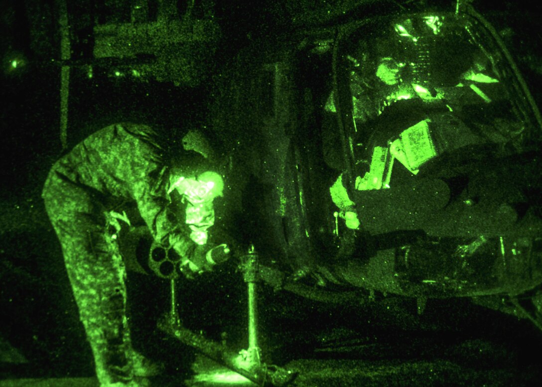 As seen through a night-vision device, a pilot gives the signal to stop pumping fuel into his OH-58 Kiowa Warrior helicopter at the forward arming and refueling point on Marine Corps Outlying Field Atlantic, N.C., Feb. 8, 2016. Army photo by Staff Sgt. Christopher Freeman
