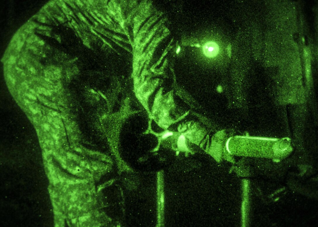 As seen through a night-vision device, a soldier loads a rocket onto an OH-58 Kiowa Warrior helicopter before the unit's aerial gunnery exercise on Marine Corps Outlying Field Atlantic, N.C., Feb. 8, 2016. Army photo by Staff Sgt. Christopher Freeman