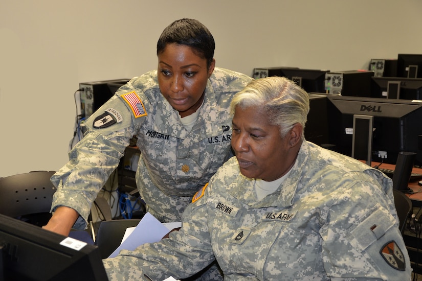 Maj. Camille Morgan, security manager and safety officer for the 915th Contracting Battalion out of Baltimore, shows Sgt. 1st Class Pamela Brown, contracting specialist, also with the 915th, how to process a de-obligation during battle assembly. 