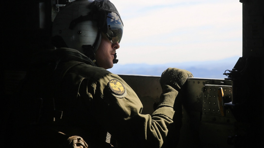 A Marine observes the objecive area below during a tactical recovery of aircraft and personnel, or TRAP, training scenario at Camp Pendleton, Calif., Feb. 10, 2015. Marine Heavy Helicopter Squadron 462, Marine Aircraft Group 16, 3rd Marine Aircraft Wing, provided aerial support for Weapons Company, 2nd Battalion, 4th Marine Regiment, 1st Marine Division during the daytime TRAP exercise. The Marine is with HMH- 462. (U.S. Marine Corps photo by Lance Cpl. Devan K. Gowans/Released)