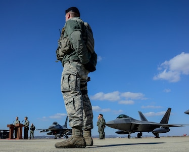 Airman 1st Class John Williams, 51st Security Forces Squadron defender, watches as Lt. Gen. Terrence O’Shaughnessy, U.S. Forces Korea deputy commander and U.S. 7th Air Force commander, and Republic of Korea Air Force Lt. Gen. Lee, Wang-Keon, ROK Air Force Operations Command commander, give remarks after a flyover in the vicinity of Osan Air Base, South Korea, in response to recent provocative action by North Korea Feb. 17, 2016. Four U.S. Air Force F-22 "Raptor" fighter aircraft from Kadena Air Base, Japan, were joined by four F-15 Slam Eagles and U.S. Air Force F-16 Fighting Falcons. The F-22 is designed to project air dominance rapidly and at great distances and currently cannot be matched by any known or projected fighter aircraft.  (U.S. Air Force photo by Senior Airman Kristin High/Released)