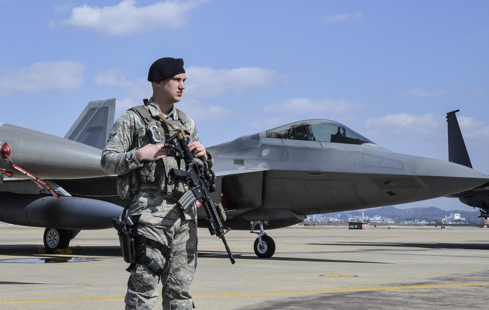 An Air Force Security Forces member stands guard next to an F22 Raptor fighter aircraft from Kadena Air Base, Japan, after it conducted a flyover in the vicinity of Osan Air Base, South Korea, in response to recent provocative action by North Korea Feb. 17, 2016. It was joined by three other Raptors, four F-15 Slam Eagles and four U.S. Air Force F-16 Fighting Falcons. The F-22 is designed to project air dominance rapidly and at great distances and currently cannot be matched by any known or projected fighter aircraft.  (U.S. Air Force photo by Tech. Sgt. Travis Edwards/Released)