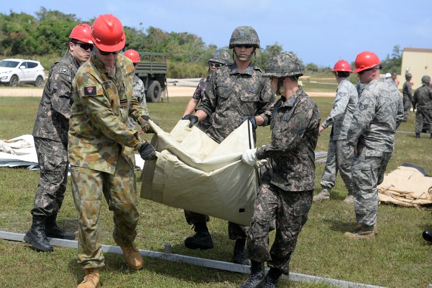 Airmen from the Royal Australian Air Force and the Republic of Korea Air Force carry a tarp during a tent building exercise Feb. 13, 2016, at Andersen Air Force Base, Guam. The exercise is a small part of the first multilateral Partner Nation Silver Flag, a U.S. Pacific Command multilateral Theater Security Cooperation Program subject matter expert exchange event designed to build partnerships and promote interoperability through the equitable exchange of civil engineer related information. (U.S. Air Force photo/Senior Airman Joshua Smoot)