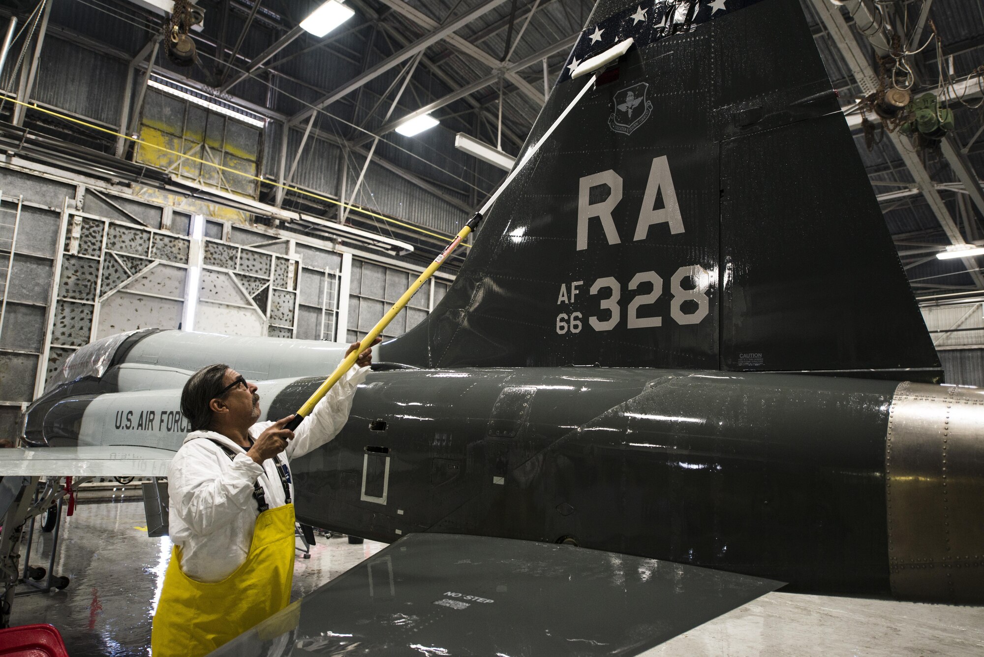 Daniel Salinas, 12th Flying Training Wing Maintenance Directorate, peels masking tape off the tail of a T-38 Talon Feb. 2 at the new wash rack at JBSA-Randolph.