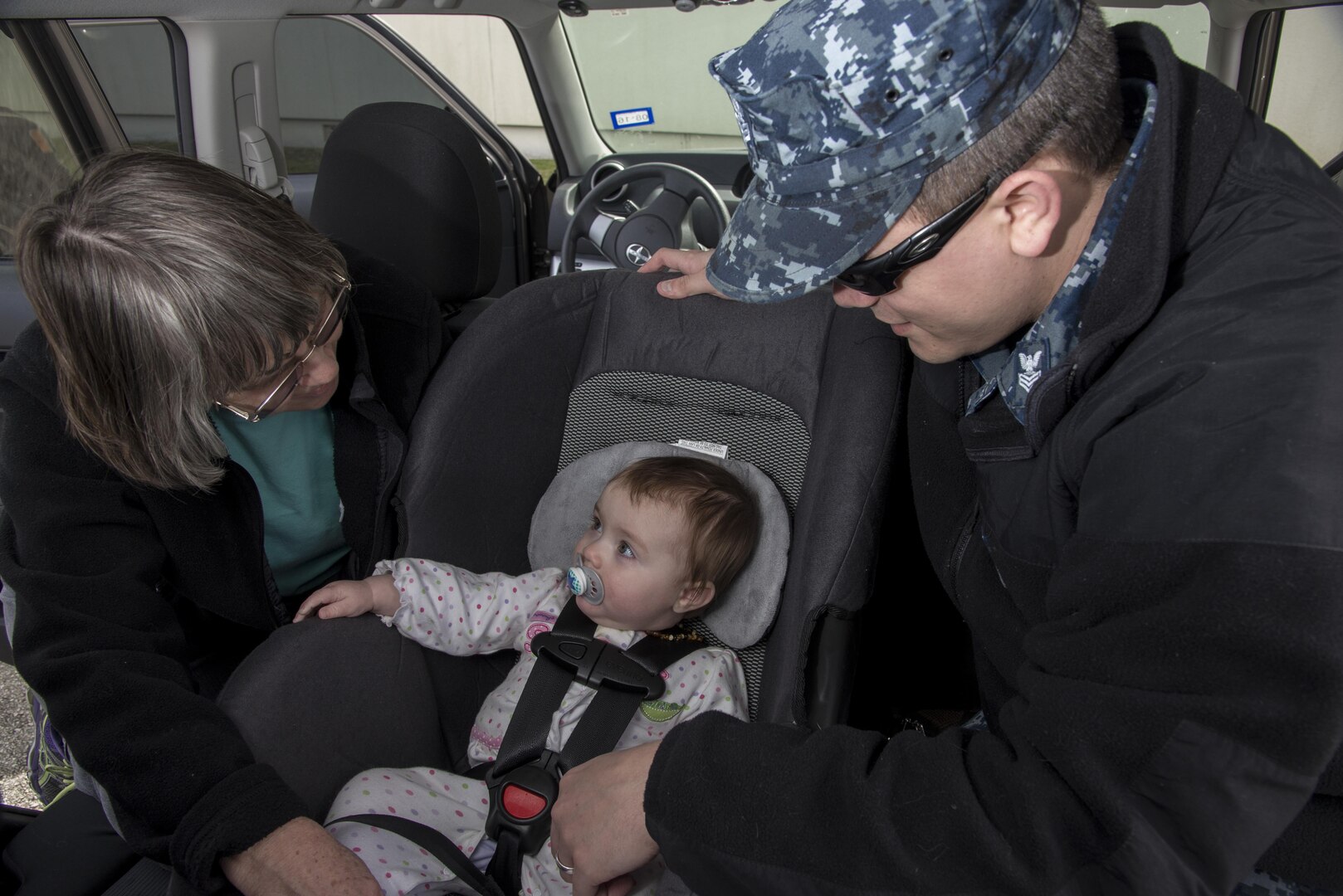 Patricia stark, Curbside Car Seat Clinic volunteer, teaches Petty Officer 1st Class Clifton Alexander, Defense Language Institute English Language Center operations specialist, how to properly install a car seat Feb. 8, 2016, at Joint Base San Antonio-Randolph, Texas. The “Curbside Car Seat Clinic,” a monthly event presented by the 359th Medical Operations Squadron Family Advocacy’s New Parent Support Program that teaches parents how to correctly install child safety seats in their vehicles. (U.S. Air Force photo by Airman 1st Class Stormy Archer/RELEASED)

