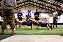Capt. Daniel Cartica (standing right), Marine officer instructor at Northwestern University, observes Northwestern University female lacrosse players performing squad push-ups at the training event he helped organize at the university’s indoor training facility, Feb. 16., 2016. Cartica holds the current world record for the World Marathon Challenge, which involves running seven marathons, on all seven continents in seven consecutive days.