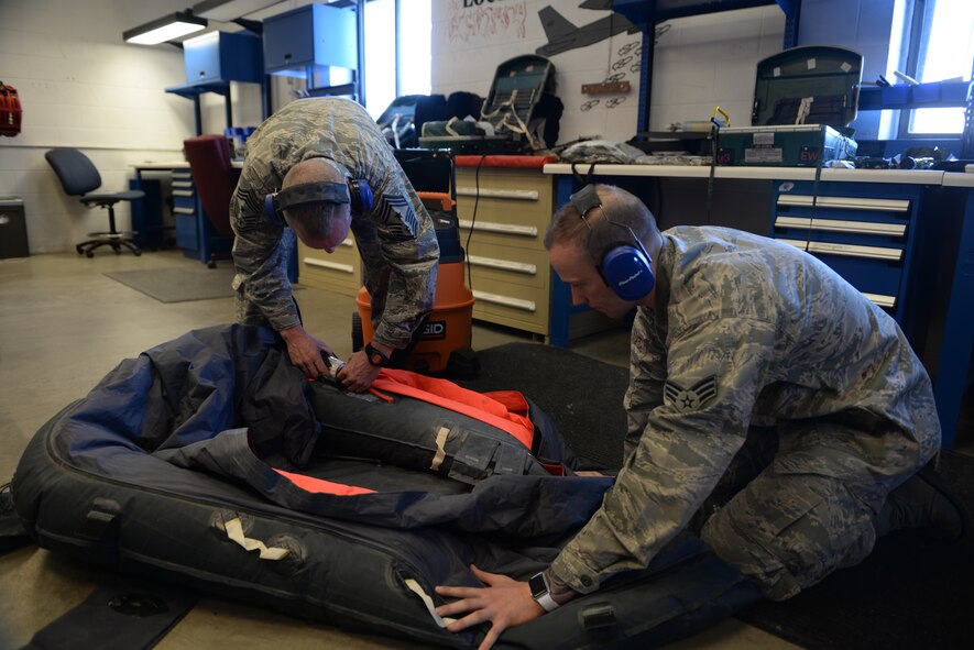 Chief Master Sgt. Geoff Weimer, 5th Bomb Wing command chief, assists Senior Airman Parker Taylor, an aircrew flight equipment journeyman assigned to the 5th Operations Support Squadron, deflate a one-man life raft at Minot Air Force Base, N.D., Feb. 12, 2016. Once deflated, the raft is folded and installed into the appropriate survival container. (U.S. Air Force photo/Airman 1st Class Jessica Weissman)