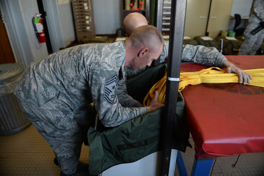Chief Master Sgt. Geoff Weimer, 5th Bomb Wing command chief, assists Senior Airman Joshua Henderson, an aircrew flight equipment journeyman assigned to the 5th Operations Support Squadron, pack a parachute for a B-52H Stratofortress at Minot Air Force Base, N.D., Feb. 12, 2016. The 90-foot drag parachute weighs approximately 200 pounds when fully packed and deploys as an aircraft lands, helping it slow down on the runway. (U.S. Air Force photo/Airman 1st Class Jessica Weissman)