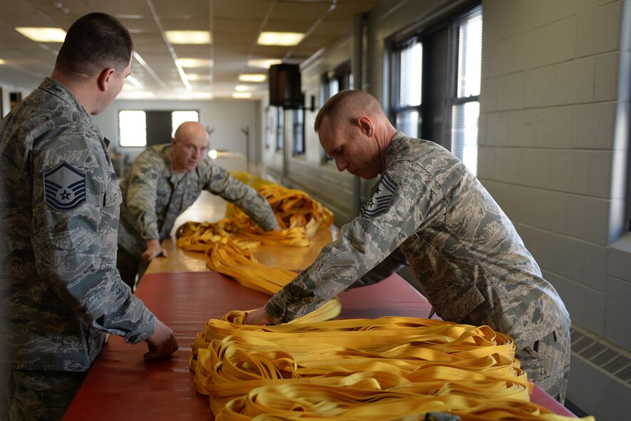Chief Master Sgt. Geoff Weimer, 5th Bomb Wing command chief, accordion folds a drag parachute with the help of Senior Airman Joshua Henderson, an aircrew flight equipment journeyman assigned to the 5th Operations Support Squadron at Minot Air Force Base, N.D., Feb. 12, 2016. This fold prepares the parachute to be packed into the case assembly, which is then installed onto the B-52H Stratofortress. (U.S. Air Force photo/Airman 1st Class Jessica Weissman)