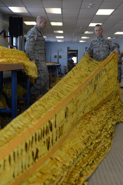 Senior Airman Joshua Henderson, an aircrew flight equipment journeyman assigned to the 5th Operations Support Squadron, explains the drag parachute inspection procedure to Chief Master Sgt. Geoff Weimer, 5th Bomb Wing command chief, at Minot Air Force Base, N.D., Feb. 12, 2016. Airmen inspect multiple drag parachutes every day for tears, holes or seam separations in the canopy. (U.S. Air Force photo/Airman 1st Class Jessica Weissman)