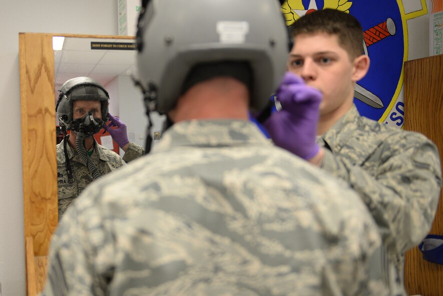 Airman 1st Class Karl Ochsenbein, an aircrew flight equipment journeyman assigned to the 5th Operations Support Squadron, assists Chief Master Sgt. Geoff Weimer, 5th Bomb Wing command chief, to ensure his oxygen mask fits properly at Minot Air Force Base, N.D., Feb. 12, 2016. The oxygen tester provides the same amount of pressure as the aircraft oxygen system up to 45,000 feet. (U.S. Air Force photo/Airman 1st Class Jessica Weissman)