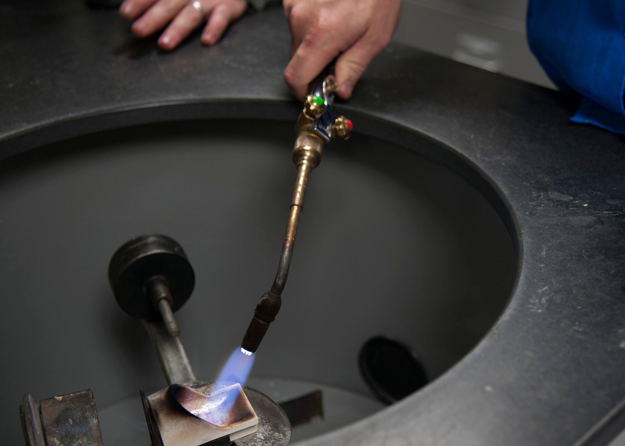 U.S. Air Force Chief Master Sgt. Aaron Bennett, 7th Bomb Wing command chief melts down gold at the 7th Medical Group Feb. 9, 2016, at Dyess Air Force Base, Texas. After the propane torch melts the gold into a liquid, the metal is then casted into a crown to use for oral procedures. (U.S. Air Force photo by Airman 1st Class Katherine Miller/Released)