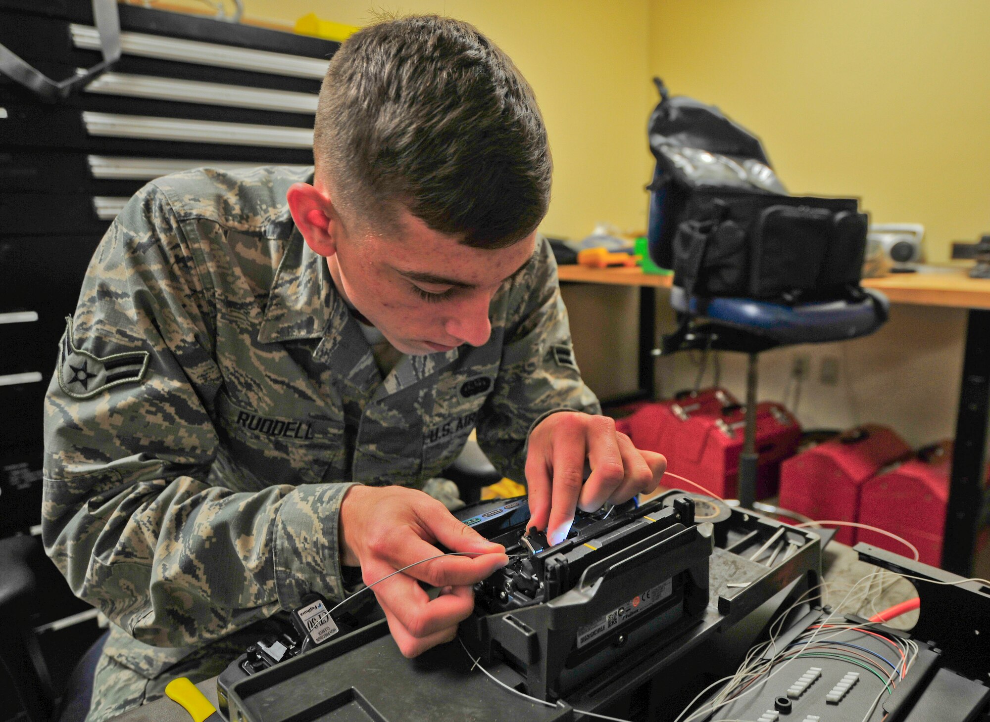 Airman 1st Class Odie Ruddell, 325th Communications Squadron cable and antenna systems technician, repairs an optical fiber Feb. 11 at building 649. These fibers transfer data more than 1,000 times faster than traditional copper wire and each fiber can support up to 2 million phone lines. (U.S. Air Force photo by Senior Airman Dustin Mullen/Released)