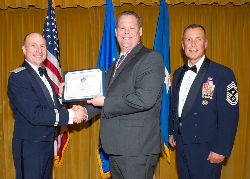 Brig. Gen. Carl Schaefer, 412th Test Wing commander (left), shakes hands with Matt Holder, 412th Communications Squadron, one of two civilians to graduate from Airman Leadership School Feb. 11. They are joined on stage by Chief Master Sgt. David Smith, 412th Test Wing command chief. (U.S. Air Force photo by Kevin North)