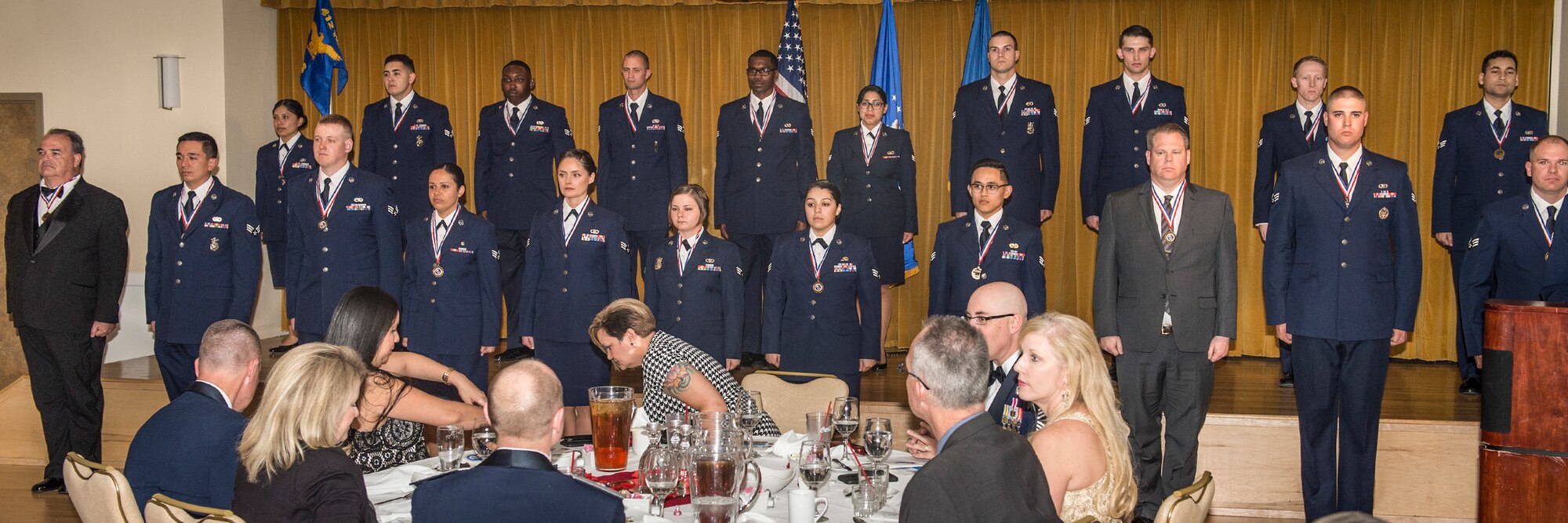 Airman Leadership School graduates stand up before the audience during their graduation ceremony at Club Muroc Feb. 11. Among the class were the first two civilian graduates here at Edwards AFB. (U.S. Air Force photo by Kevin North)