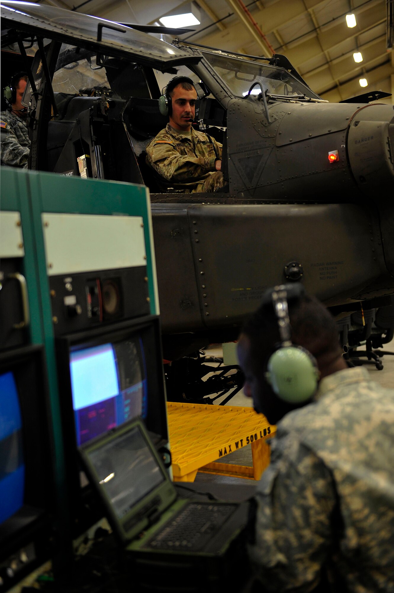 U.S. Army Pfc. Cedric Ebrottie, a student with 128th Aviation Brigade, 1st Battalion, 222nd Aviation Regiment, speaks with fellow student, Spc. Dominic Freitas, during an armament, electronic and avionics systems repair course at Fort Eustis, Va., Feb. 11, 2016. Students perform maintenance operation checks on a Boeing AH-64 Apache to troubleshoot aircraft components. (U.S. Air Force photo by Airman 1st Class Breonna Veal)