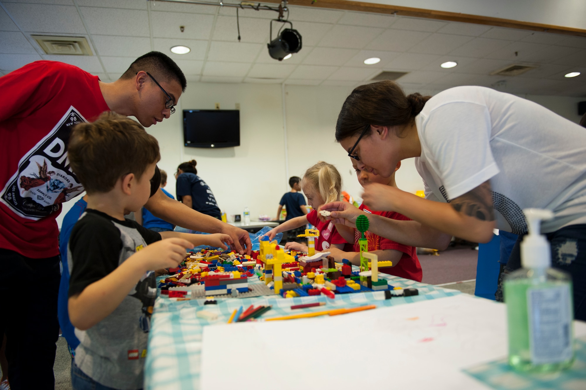 U.S. Air Force Airman 1st Class Robert Cabiz, 18th Logistics Readiness Squadron material management journeyman, and Airman 1st Class Angelica Torres, 18th LRS material management journeyman, assist children during Kadena’s Lego Master Builder Challenge, Feb 13, 2016, at Kadena Air Base, Japan. The children, kindergarten and first grade students, were tasked with designing and creating an aircraft hangar in an effort to inspire them to apply science, technology, engineering and math to solve real world challenges. (U.S. Air Force photo by Airman Zackary A. Henry)