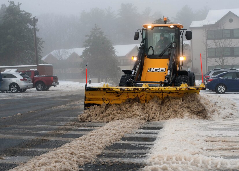 Tim Pickering, a member of the 66th Civil Engineering Division’s Roads and Grounds team, removes snow from a parking lot on base Feb 16. Civil engineers were busy throughout the day cleaning up after the most recent winter storm hit the area. (U.S. Air Force photo by Jerry Saslav)