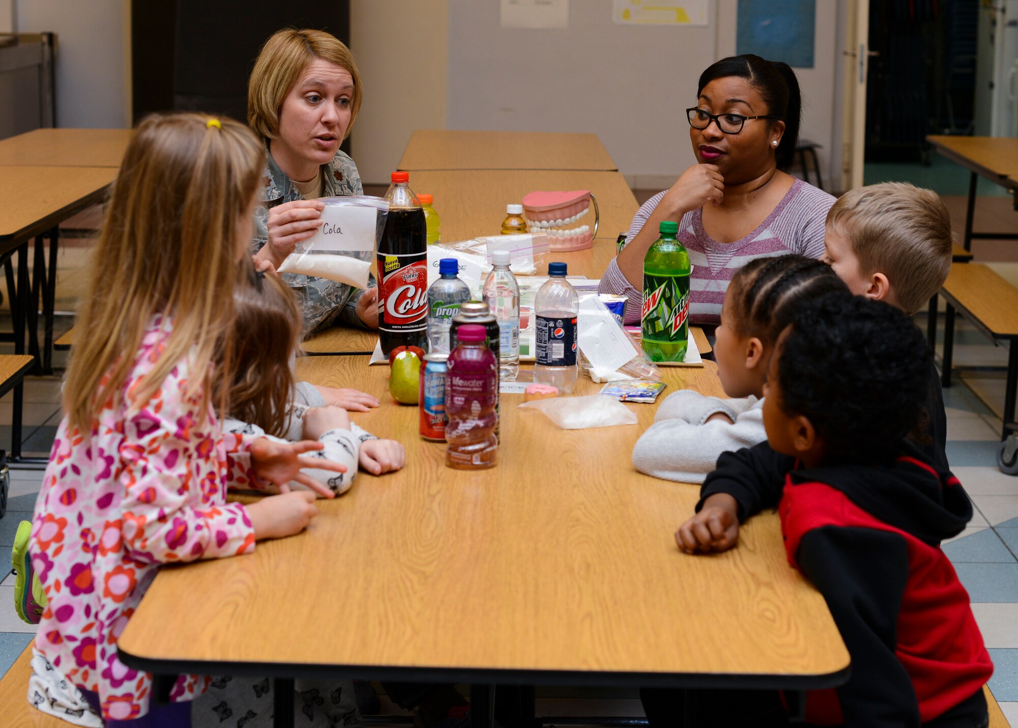 (Second from left) U.S. Air Force Maj. Amy Brown, 31st Dental Squadron dentist, and Grace Leslie-Valentine, 31st DS dental assistant, teach Aviano Elementary School kindergartners the dangers of sugary foods during a National Children’s Dental Health Month event, Feb. 16, 2016, at Aviano Air Base, Italy. The children watched an educational video, learned how sugar impacts their teeth and practiced proper brushing and flossing. (U.S. Air Force photo by Senior Airman Austin Harvill/Released)