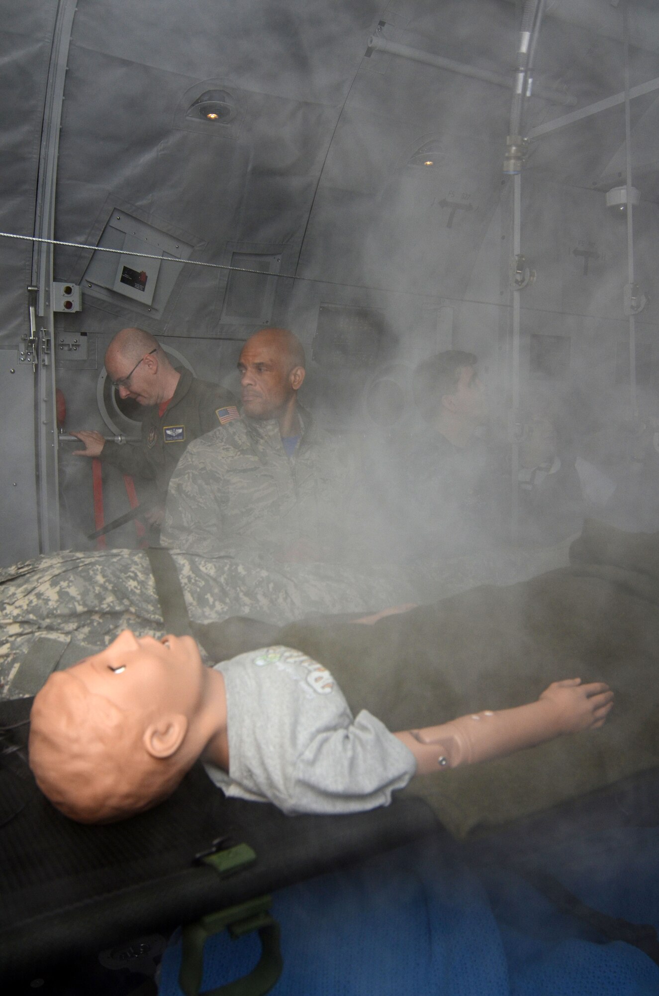 Maj. Chad Corliss, Director of Operations from the 94th Aeromedical Evacuation Squadron demonstrates one of the capabilities of a newly installed aeromedical evacuation training simulator for members of the Honorary Commanders Association during Dobbins Day, a tour conducted on Dobbins Air Reserve Base, Ga. Feb. 12, 2016. Corliss filled the patient area with non-toxic smoke simulating an on-board fire situation. The trainer designed as the cargo area of a C-130 Hercules, simulates various emergency conditions experienced by medical personnel during evacuation scenarios. (U.S. Air Force photo/Don Peek)