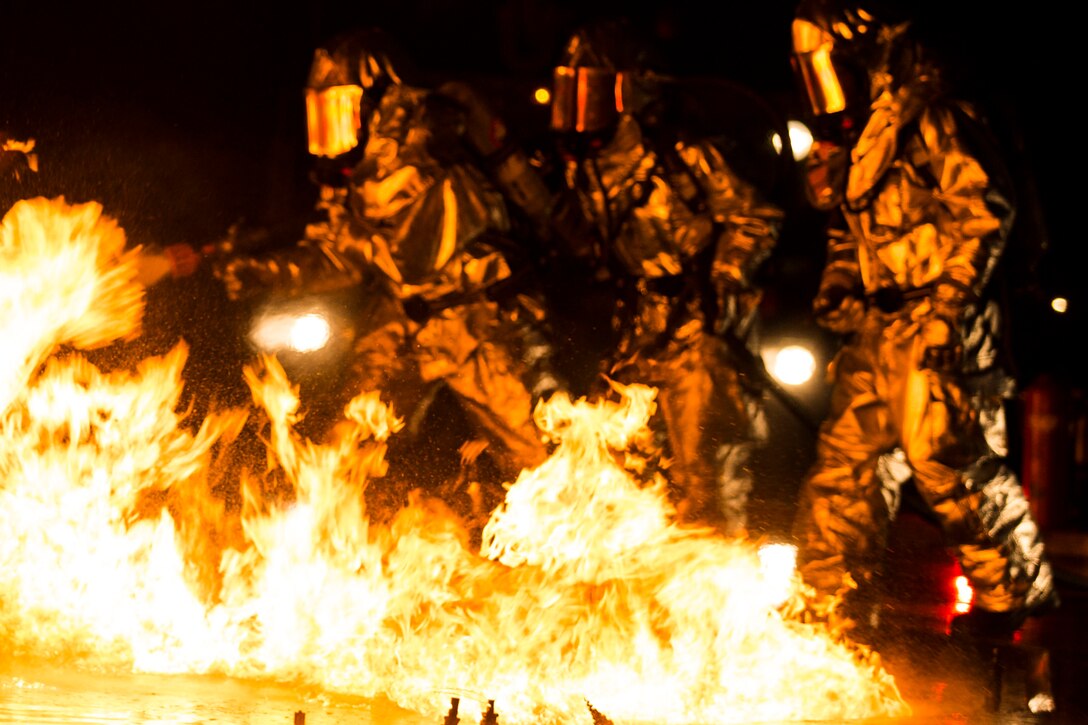 Marines extinguish a fire during a controlled burn training exercise aboard Marine Corps Air Station Beaufort Feb. 17. The Marines are wearing heat resistant suits that can withstand up to 2,100 degrees of heat and a breathing apparatus attached to a canister that provides them oxygen as they navigate through the fire. The Marines are with Aircraft Rescue and Firefighting. (U.S. Marine Corps Photo by Lance Cpl. Jonah Lovy/Released)
