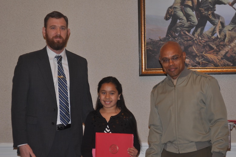 Mayor Kevin Brown and Lt. Col. Douglas Lemott, Jr. present Nyah, age 9, with the award for winning the Black History Month essay contest in the elementary school category.