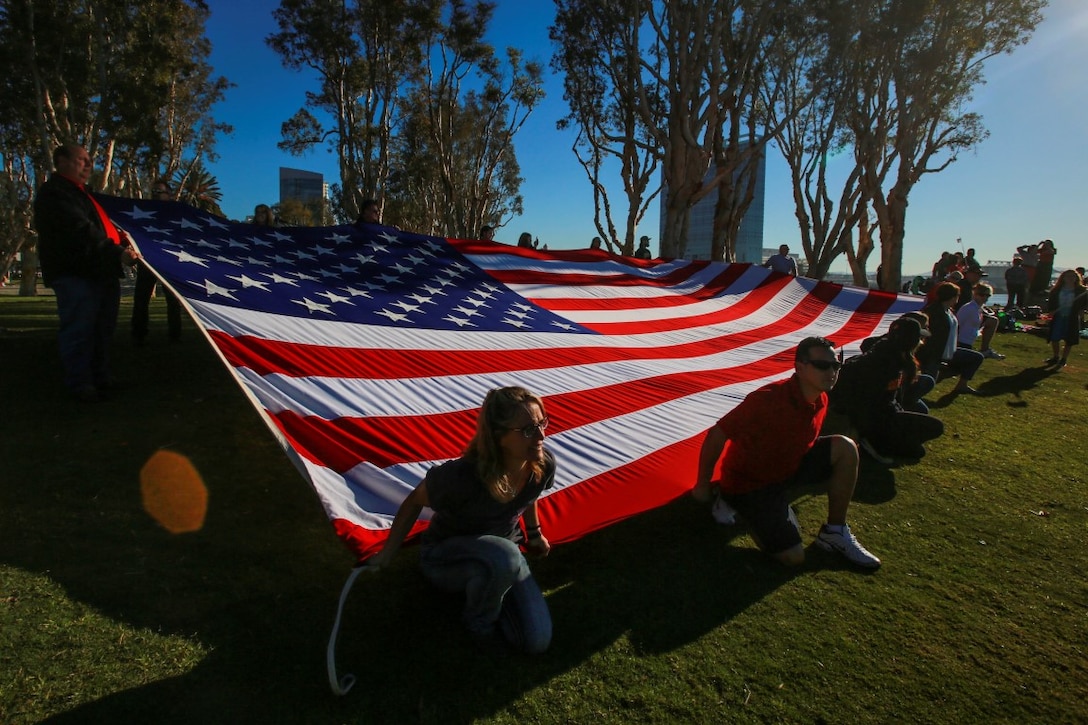 The family and friends of Marines and sailors deploying with the 13th Marine Expeditionary Unit display a large flag on the shore as the Boxer Amphibious Ready Group passes by in San Diego Feb. 12, 2016. The 13th MEU is capable of conducting amphibious operations, crisis response and limited contingency operations and is beginning an estimated six month deployment to the Western Pacific and Middle East. (U.S. Marine Corps photo by Lance Cpl. Caitlin Bevel)