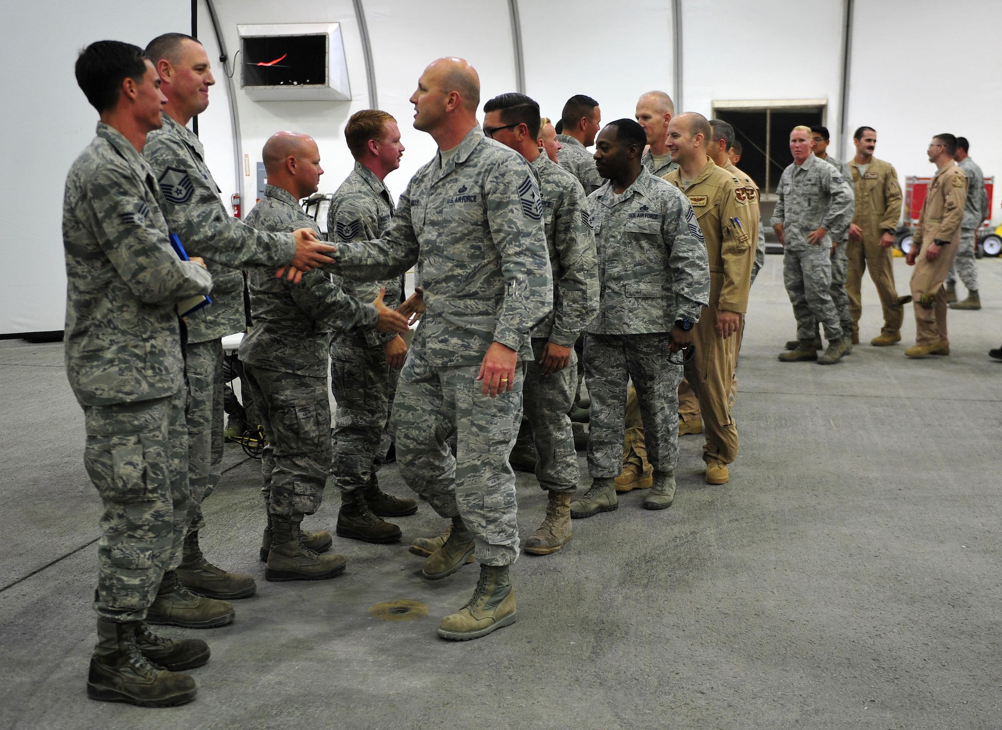 Chief Master Sgt. Charles Mills, 380th Air Expeditionary Wing command chief, congratulates 380th Expeditionary Aircraft Maintenance Squadron Airmen after an awards ceremony at an undisclosed location in Southwest Asia, Feb. 16, 2016. In addition to the medals, the maintainer’s efforts garnered them the AFCENT Ground Safety Award of Distinction for February 2016. (U.S. Air Force photo by Staff Sgt. Kentavist P. Brackin/Released)