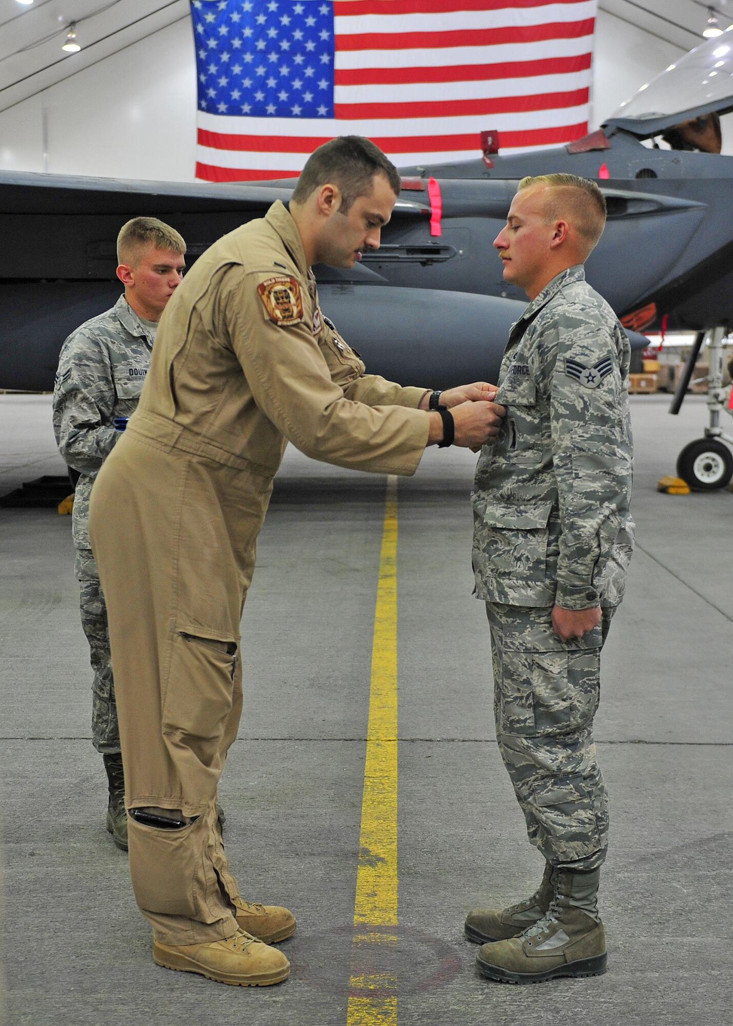 U.S. Air Force 1st Lt. Nicholas, F-15E Strike Eagle fighter pilot assigned to the 391st Expeditionary Fighter Squadron, pins an Air Force Commendation Medal on Senior Airman Nash Camden, a 380th Expeditionary Aircraft Maintenance Squadron weapons load crew member, during an awards ceremony at an undisclosed location in Southwest Asia, Feb. 16, 2016. Nicholas is one of two aircrew members who were inside a taxiing F-15 when a hydraulic fluid leak on the aircraft’s hot brakes set it afire Dec. 2, 2015. (U.S. Air Force photo by Staff Sgt. Kentavist P. Brackin/Released)