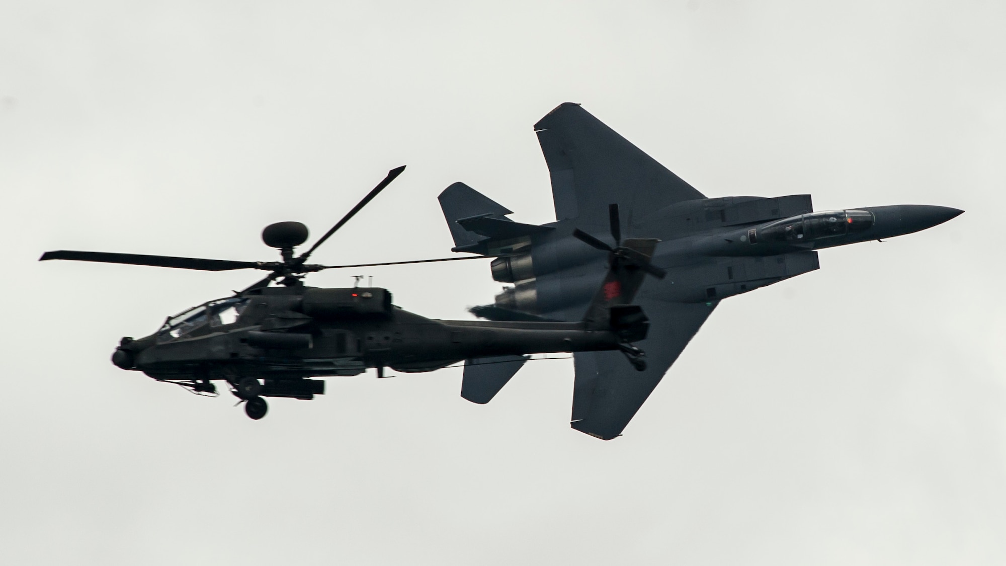 A Republic of Singapore air force F-15SG Strike Eagle flies past a Singapore army AH-64D Apache Longbow attack helicopter as part of an aerial demonstration during the Singapore International Airshow at Changi International Airport, Singapore, Feb. 18, 2016. Singapore is a strong partner with the U.S. that provides mutual training and cooperation opportunities between the two nations’ military forces. (U.S. Air Force photo by Capt. Raymond Geoffroy/Released)