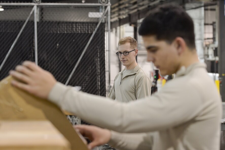 Senior Airman Christopher Shields, 436th Aerial Port Squadron packing and shipping clerk, watches Airman 1st Class Yasel Berrocal, 436th APS packing and crating clerk, confirm shipping information as the two prepare shipments for commercial pick-up Feb. 10, 2016, at Dover Air Force Base, Del. Clerks like Shields and Berrocal prepare and ship important items across the world daily. (U.S. Air Force photo/Greg L. Davis)