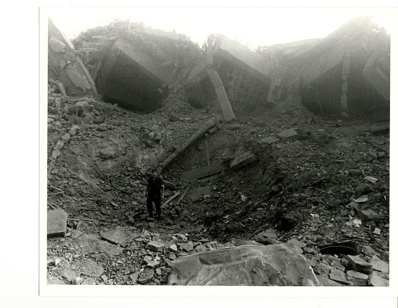 Naval Investigative Service Special Agent Grant McIntosh stands in the rubble of what was a military barracks at the Beirut International Airport. A terrorist slammed a truck bomb into the side of the building in October of 1983, killing 220 Marines, eighteen Sailors and three Soldiers. McIntosh and a Marine CID agent were working elsewhere in Beirut at the time of the bombing and were the first American law enforcement on the scene.