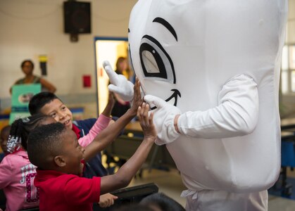 Patrick Miller, 628th Medical Group chief of preventative dentistry, interacts with children at Lambs Elementary School to promote good dental hygiene on Feb. 11, 2016. To ensure the presentation as child friendly, the dental clinic used a small cartoon instructional video, as well as a small skit where the dental clinic members dressed up as such things as a tooth, a toothbrush, dental floss, a tube of toothpaste and the tooth fairy. (U.S. Air Force photo/Airman 1st Class Thomas T. Charlton)