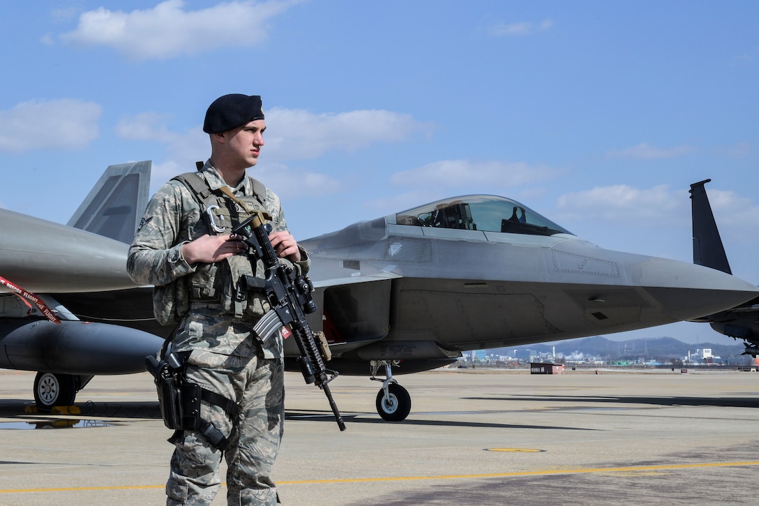 An Air Force Security Forces member stands guard next to an F-22 Raptor fighter aircraft following a flyover near Osan Air Base, South Korea, Feb. 17, 2016. Four Raptors, four South Korean F-15 Slam Eagles and four U.S. Air Force F-16 Fighting Falcons demonstrated capabilities in response to recent provocative actions by North Korea. Air Force photo by Tech. Sgt. Travis Edwards