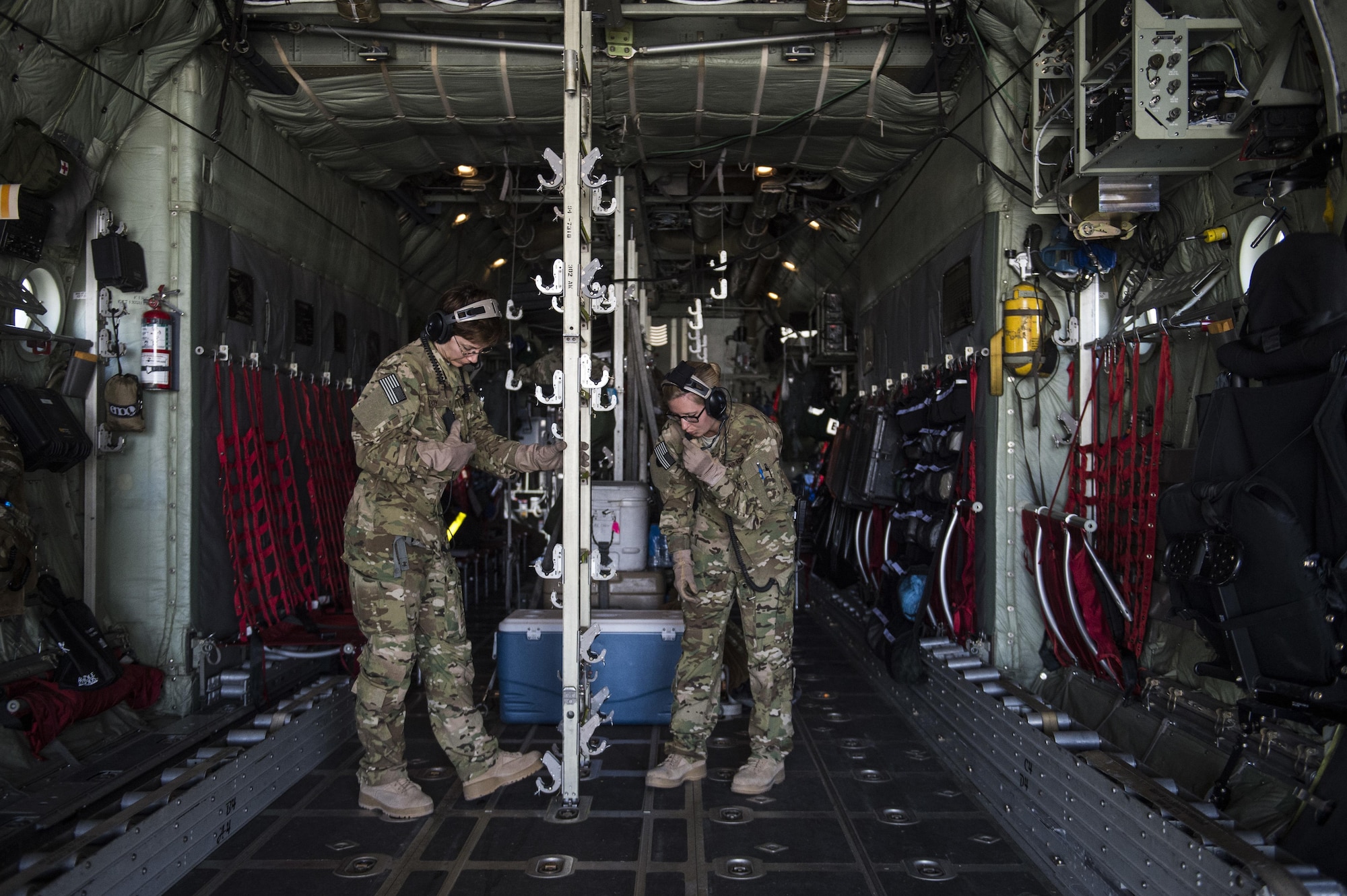 U.S. Air Force Capt. Tracie, (Left) and Senior Airman Haley, (Right) adjust the configuration inside of an Air Force C-130 Hercules during an aerovac mission from Al Udeid Air Base, Qatar, Feb. 11, 2016. Coy and Lecomte are assigned to the 379th Expeditionary Aeromedical Evacuation Squadron.  (U.S. Air Force photo by Staff Sgt. Corey Hook/Released)