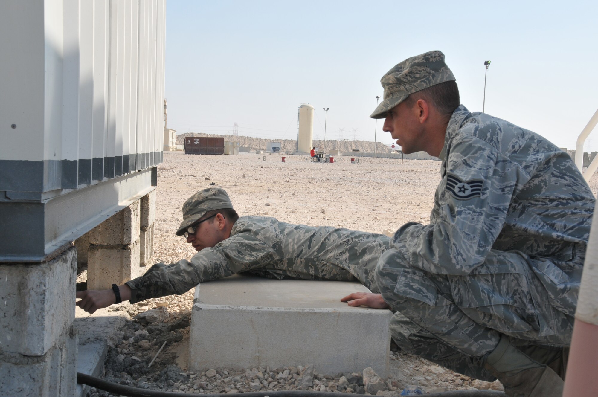 Staff Sgt. Kevin Burger (right), 379th Expeditionary Civil Engineer Squadron Cadillac maintenance team lead and Airman 1st Class Roger Jama (left), 379th ECES plumber, trouble shoot overflowing toilets in a Cadillac Feb. 12 at Al Udeid Air Base, Qatar. Both Burger and Jama are members of the 379th ECES facility maintenance team at AUAB. (U.S. Air Force photo by Tech. Sgt. Terrica Y. Jones/Released)