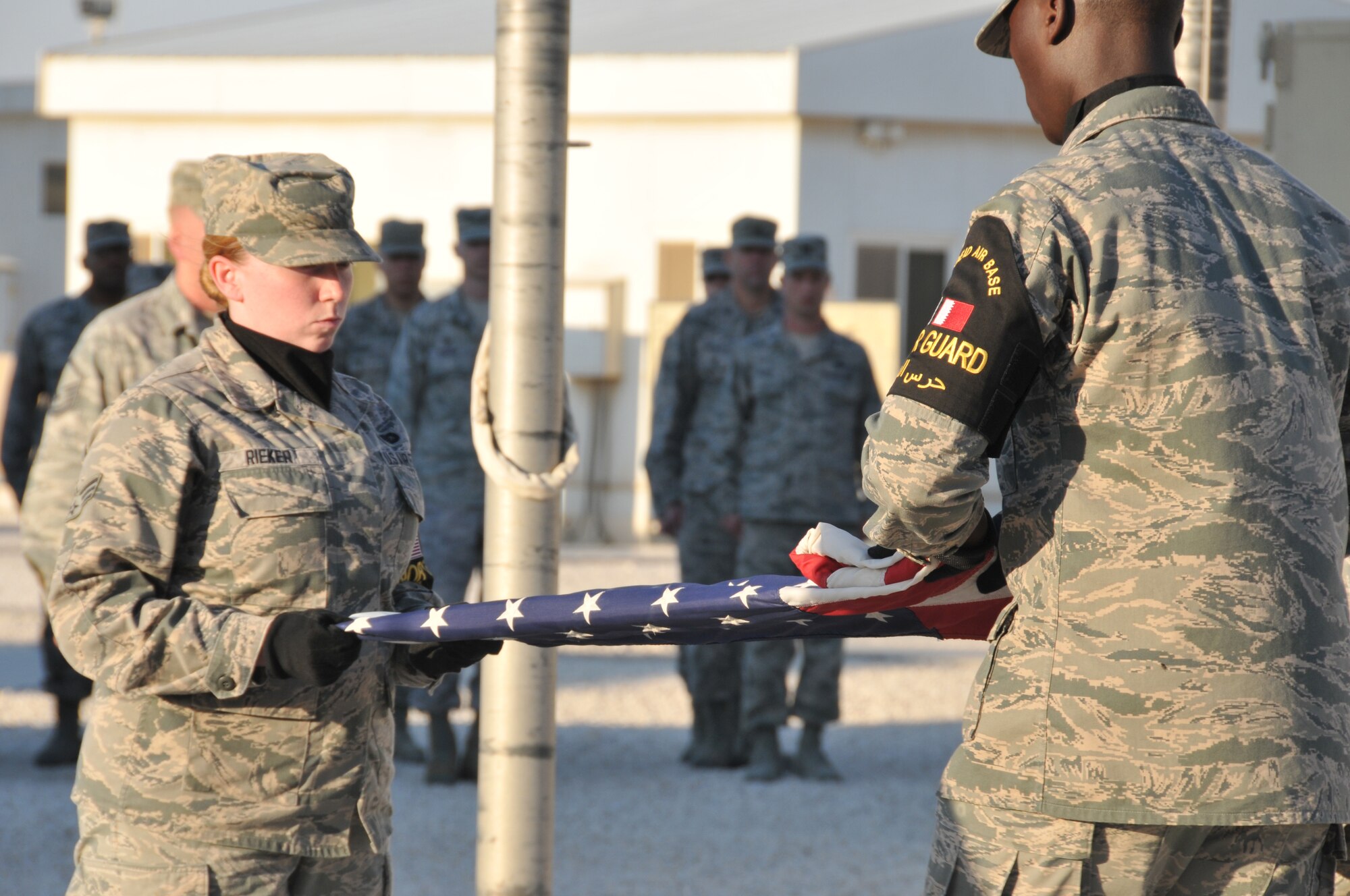 Senior Airman Gabrielle Rieker (left) and Senior Airman Isaac Darko (right), Honor Guard members fold, the U.S. flag during a retreat ceremony to commemorate George Washington’s Birthday, Feb. 15, at Al Udeid Air Base, Qatar. (U.S. Air Force photo by Tech. Sgt. Terrica Y. Jones/Released)