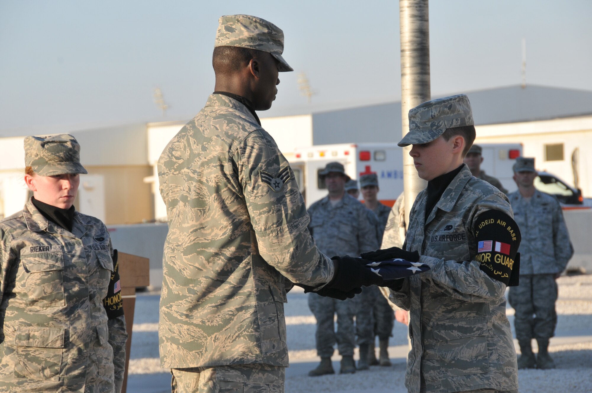 Senior Airman Isaac Darko (left) passes the U.S. flag to Senior Airman Nikole Warn (right), securing the flag at the end of the retreat ceremony, Feb. 15, at Al Udeid Air Base, Qatar. The ceremony was held to honor George Washington’s Birthday. (U.S. Air Force photo by Tech. Sgt. Terrica Y. Jones/Released)