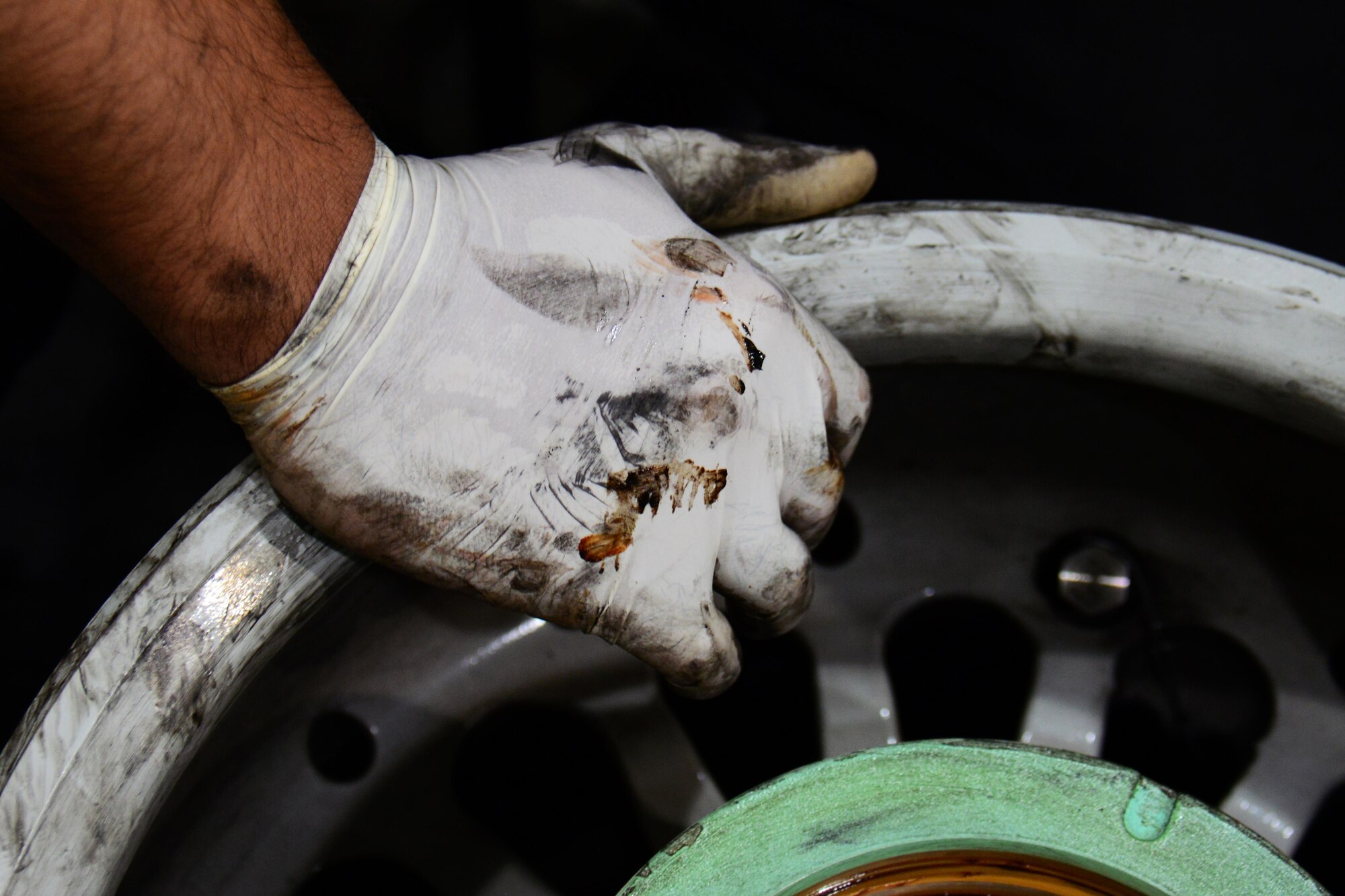 Staff Sgt. Abraham Ponce, 379th Expeditionary Maintenance Squadron aerospace maintenance craftsman, from Odessa, Texas, rests his hand on a wheel at Al Udeid Air Base, Qatar Feb. 16. Cleaning every wheel by hand is part of the process of wheel and tire repair. During the cleaning process, Ponce inspects the wheel for cracks and signs of corrosion. (U.S. Air Force photo by Tech. Sgt. James Hodgman/Released)