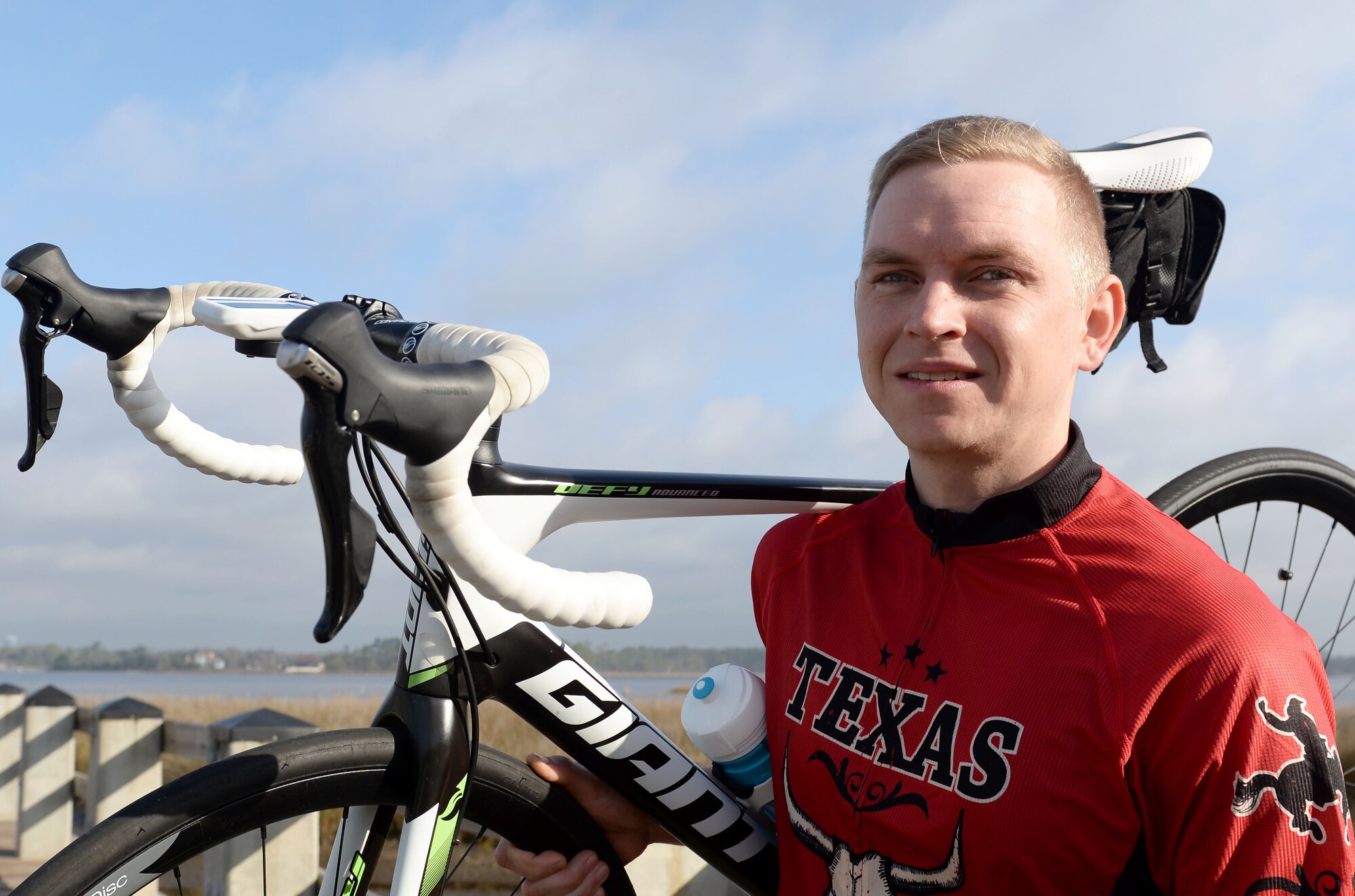 Staff Sgt. Evan Gossell, 338th Training Squadron instructor, poses for a photo with his road bike at the base marina, Feb. 12, 2016, Keesler Air Force Base, Miss. Gossell suffered an Ischemic Stroke in 2013 at age 26. After re-learning how to walk and talk, he became an instructor at Keesler and was recently accepted into the Air Force Cycling Team.