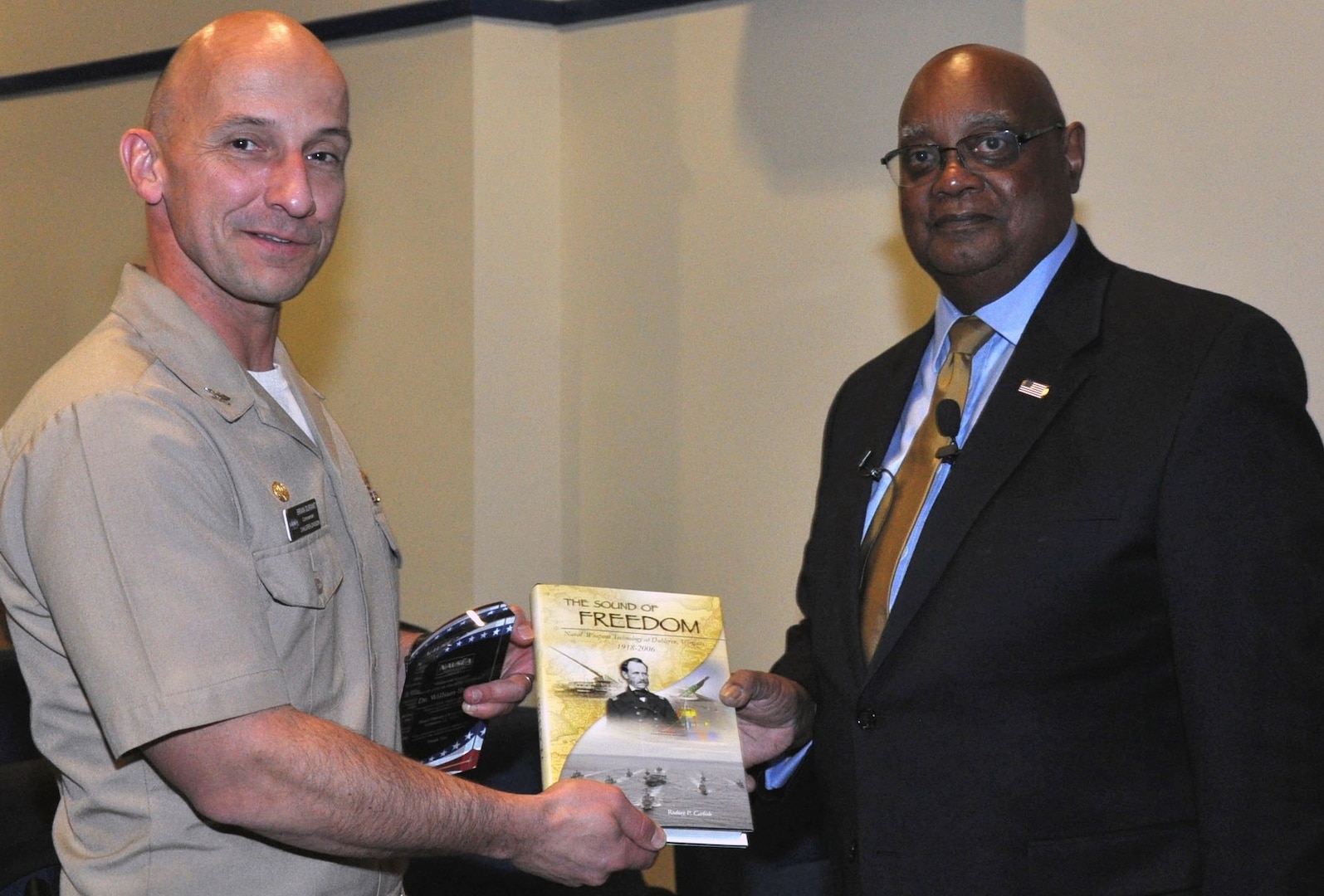 DAHLGREN, Va. - Capt. Brian Durant, Naval Surface Warfare Center Dahlgren Division (NSWCDD) commander, presents the Dahlgren history book, "The Sound of Freedom," to Dr. William Bundy, Gravely Naval Warfare Research Group director, at the 2016 Black History Month Observance, Feb. 11.  "The research and development progress that was shared with me on the railgun and directed energy systems was very reassuring," said Bundy, a U.S. Naval War College professor who toured NSWCDD electromagnetic railgun and directed energy facilities after inspiring a military and civilian audience with his keynote speech at the observance. "Those capabilities will certainly deliver advantages for our maritime forces.  It was absolutely encouraging to witness first-hand the remarkable effort and work that is continuing today at Dahlgren."  