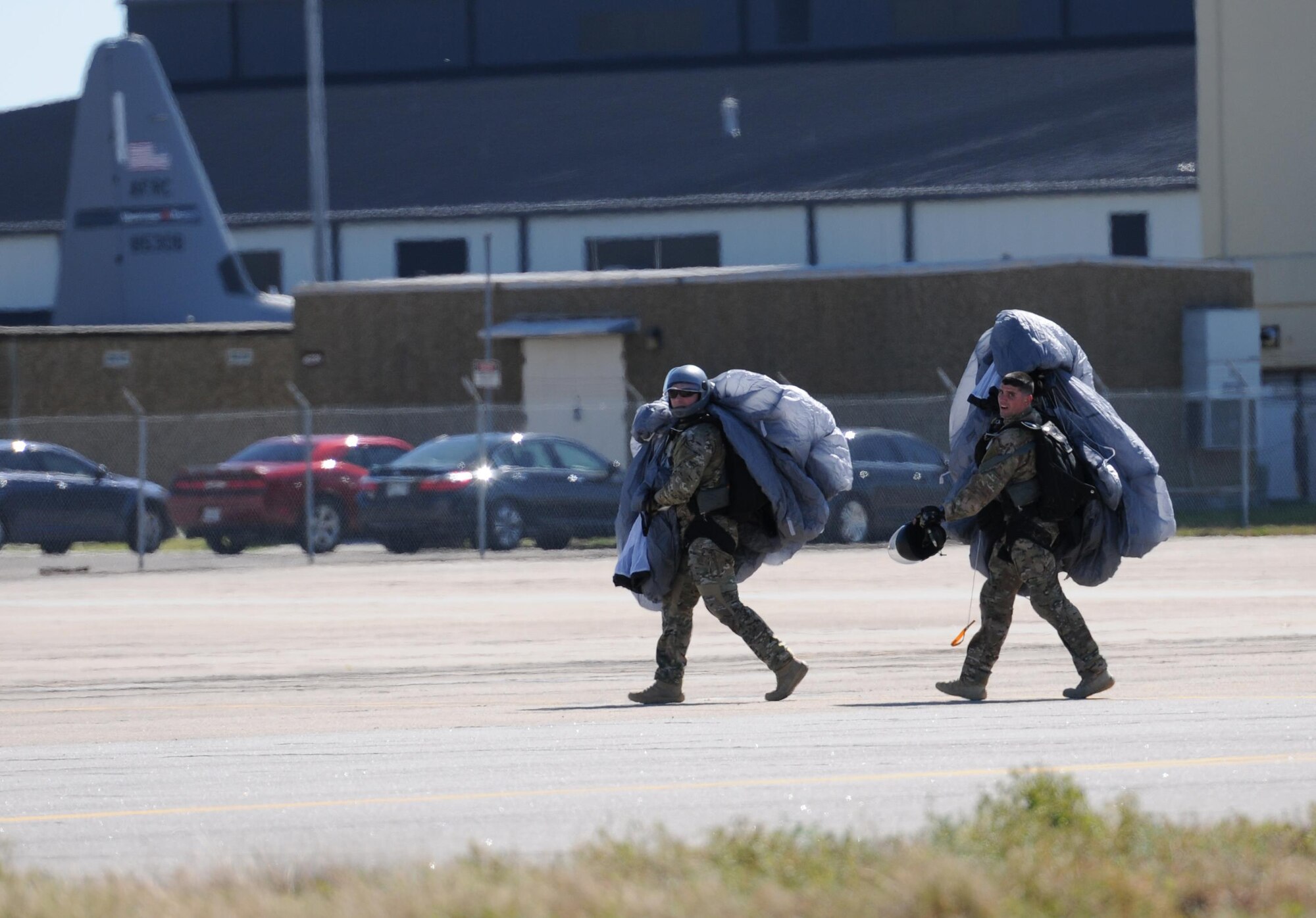 Master Sgt. Yuri and Tech. Sgt. Timothy, 334th Training Squadron combat control instructors, carry their parachutes across the flight line following a jump Feb. 17, 2016, Keesler Air Force Base, Miss. Keesler’s battlefield Airmen instructors periodically perform the routine training exercise to maintain their proficiency. (U.S. Air Force photo by Kemberly Groue)