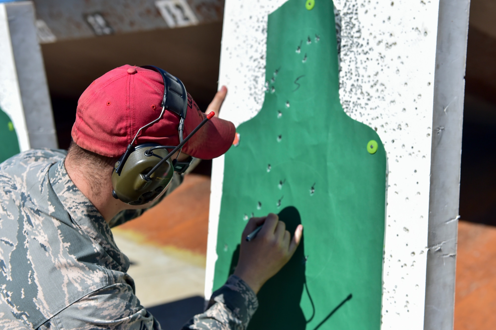 Staff Sgt. Darrin Miller, a combat arms training and maintenance instructor with the 1st Special Operations Security Forces Squadron, counts bullet holes on an M9 pistol qualification target at the CATM range, Hurlburt Field, Fla., Feb. 17, 2016. CATM instructors are weapon specialists trained to ensure Airmen are prepared to deploy by being qualified to use and maintain their weapons. (U.S. Air Force photo by Senior Airman Jeff Parkinson)
