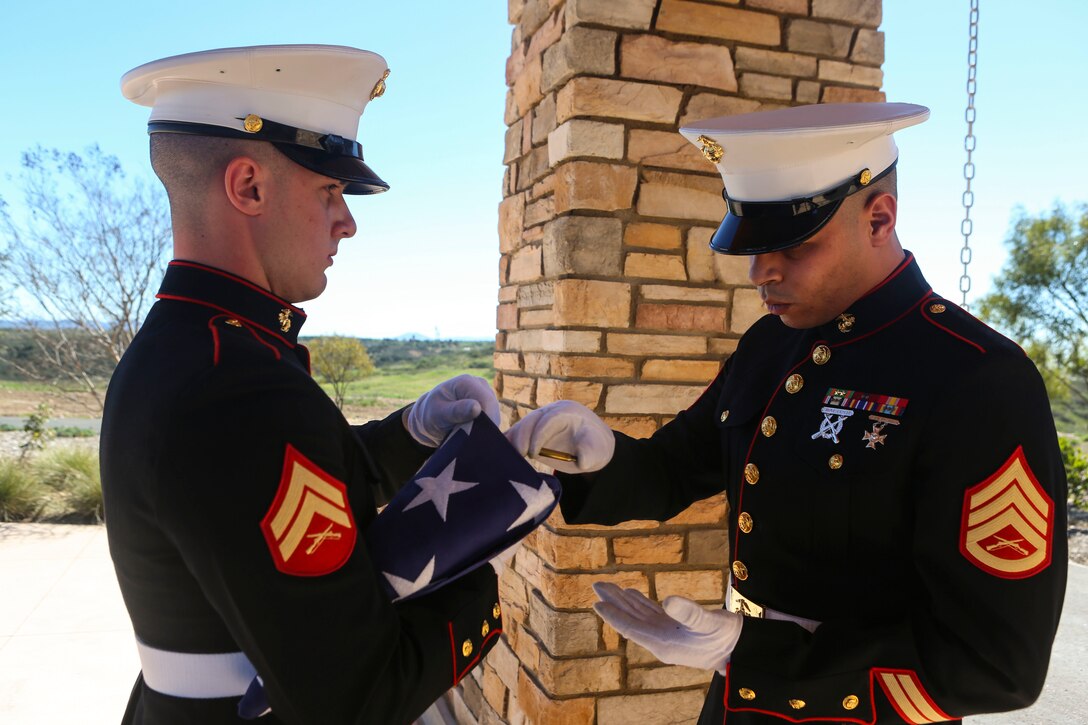 Staff Sgt. Caba places casings from the 21-gun salute inside the flag before handing it to the daughter of the deceased at a funeral aboard Miramar National Cemetery, San Diego, Feb. 16. Funeral detail honors a military tradition for fallen active-duty members and veterans alike. The tradition includes the playing of “Taps,” the folding of an American flag to be presented to the next-of-kin of the deceased, and the 21-gun salute. (U.S. Marine Corps photo by Lance Cpl. Harley Robinson/Released)