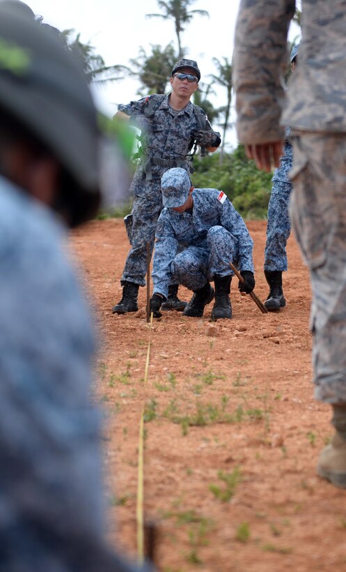Japan Air Self-Defense Force Tech. Sgt. Kei Nakao, equipment operator, watches as Republic of Singapore Air Force Military Expert 1 John Chow, crater repair instructor, measures where to place a stake during Partner Nation Silver Flag, Feb. 14, 2016, at Andersen Air Force Base, Guam. During the first multilateral Partner Nation Silver Flag, instructors from the 554th RED HORSE Squadron partnered with engineers from the Royal Australian Air Force, RSAF, Republic of Korea Air Force and the JASDF to exchange information on subjects from command and control, electrical, power production, heavy repair and emergency management. (U.S. Air Force photo by Senior Airman Joshua Smoot/Released)