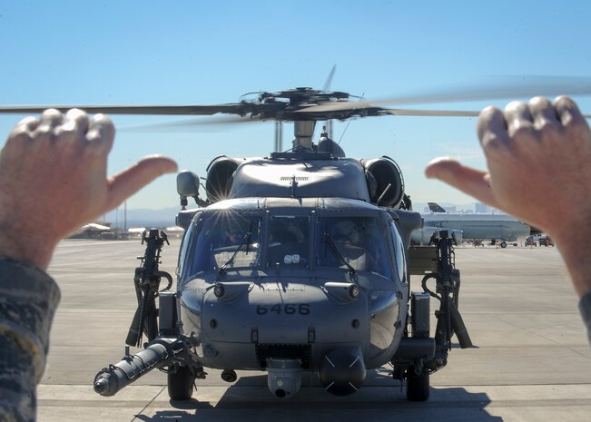 A crew chief from the 210th Rescue Squadron, Joint Base Elmendorf-Richardson, Alaska, gives a signal to pilots before they take off to participate in a mission during Red Flag 16-1 Feb. 11, 2016, at Nellis Air Force Base, Nev. While participating in Red Flag, pilots have to adjust to the warmer weather by flying in higher altitudes and conserving fuel. (U.S. Air Force photo by Senior Airman Jake Carter)