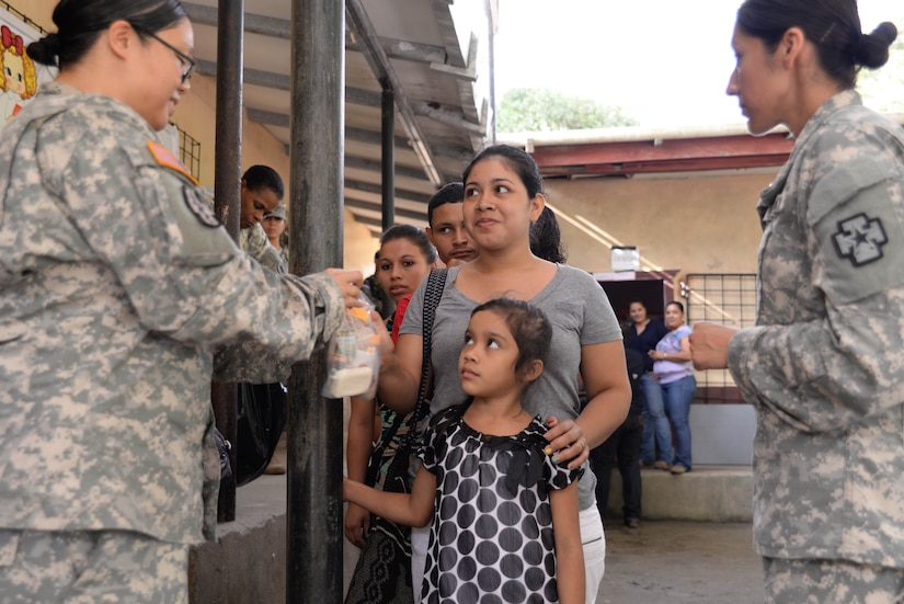 U.S. Army Sgt. Mary King, preventative medicine technician, gives a woman a bag of preventative supplies during a medical readiness training exercise in the Cortes Department, Honduras, Feb. 18, 2016. Preventative medicine aims to stop sickness before it spreads by providing vitamins, soap, and other essential items.  (U.S. Air Force Photo by Staff Sgt. Westin Warburton/Released)
