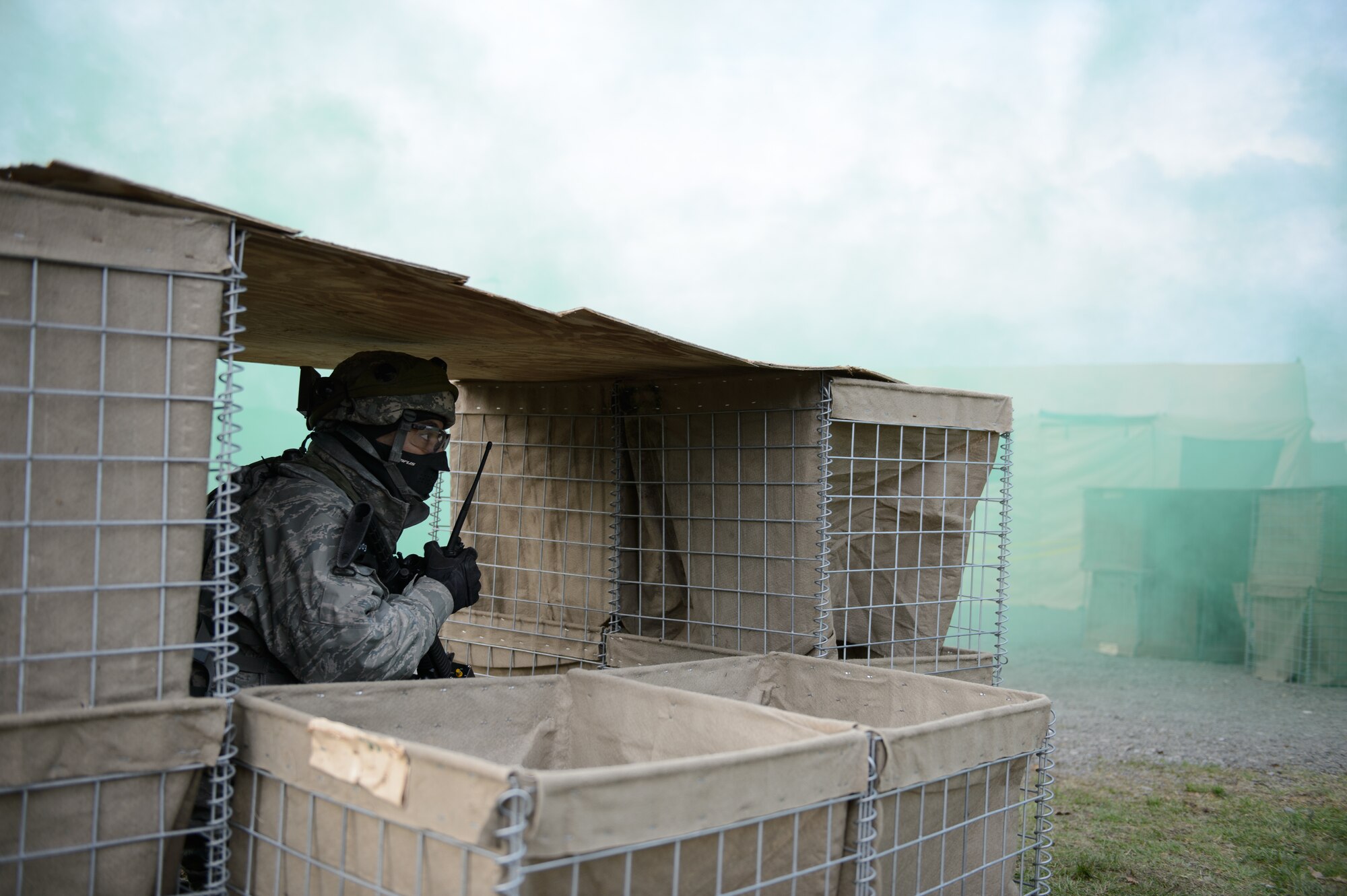 A 1st Combat Communications Squadron Airman makes a call on a radio as instructors release mock mortars on a compound Feb. 12, 2016, at Ramstein Air Base, Germany. The 1st CBCS conducts regular deployment skills training to prepare Airmen for any situation they may encounter. (U.S. Air Force photo/Staff Sgt. Armando A. Schwier-Morales)